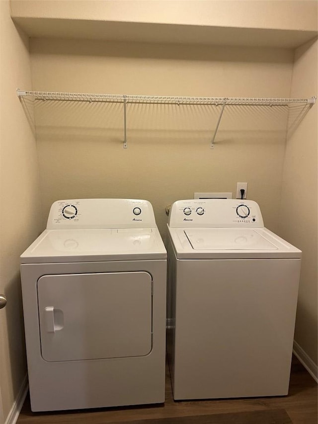 washroom with dark wood finished floors, laundry area, washer and dryer, and baseboards