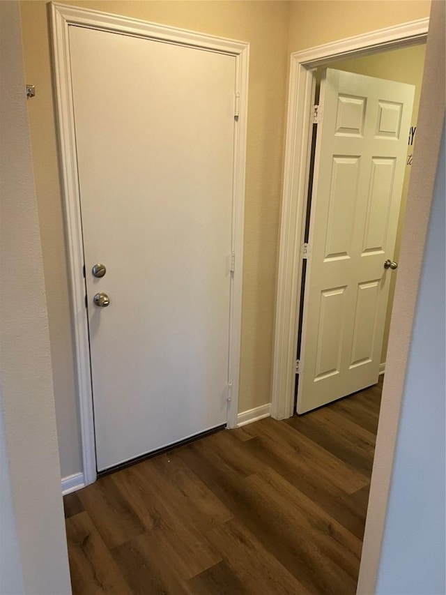 corridor featuring baseboards and dark wood-style floors