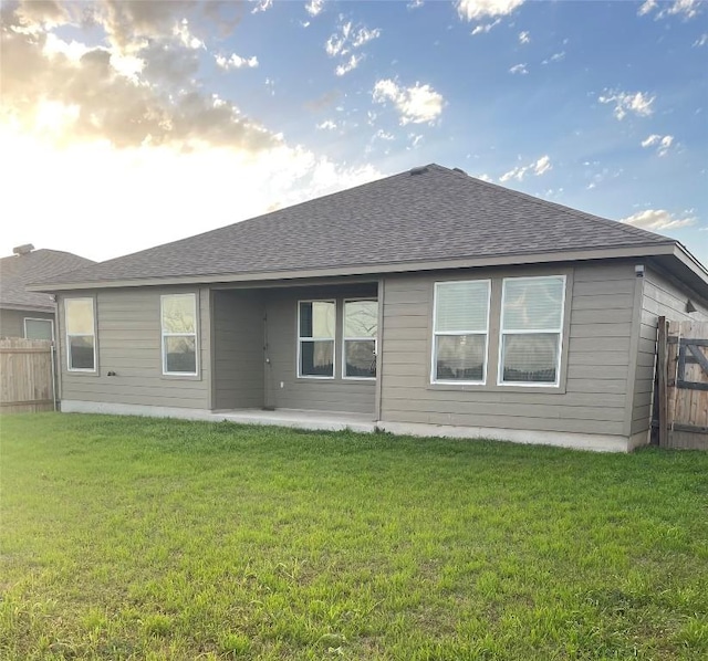 back of property featuring a patio area, a lawn, fence, and roof with shingles