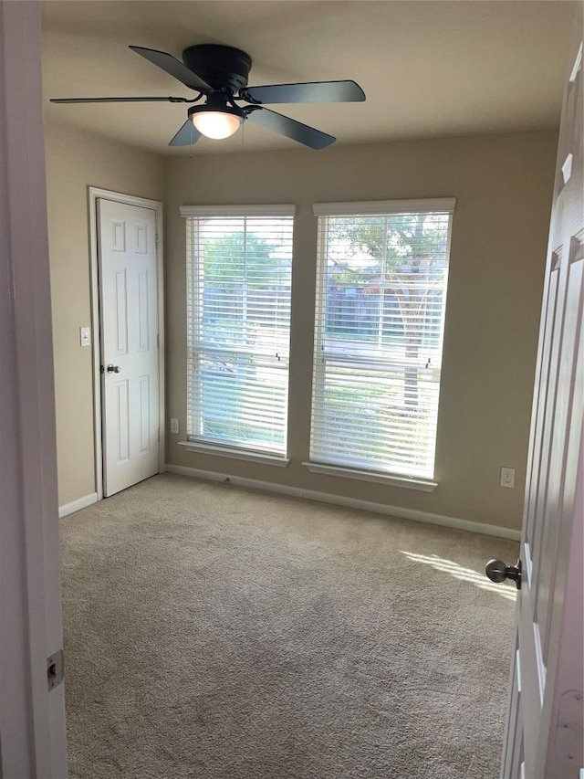 empty room featuring light carpet, baseboards, and ceiling fan