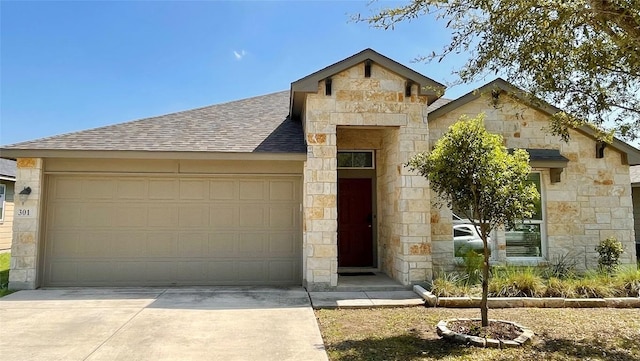 view of front facade featuring stone siding, an attached garage, concrete driveway, and roof with shingles