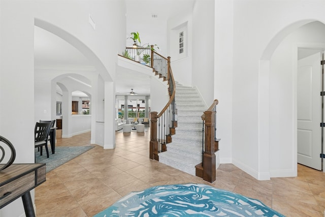 entryway featuring tile patterned flooring, stairway, baseboards, and a towering ceiling