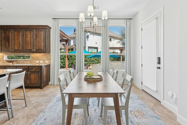 dining room featuring light tile patterned floors, visible vents, baseboards, and a chandelier