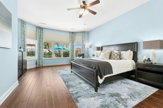 bedroom with visible vents, baseboards, wood finished floors, and a ceiling fan