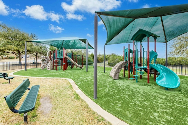 communal playground featuring a yard and fence