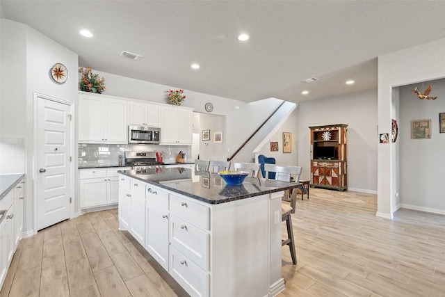 kitchen featuring visible vents, light wood-style flooring, appliances with stainless steel finishes, backsplash, and a center island