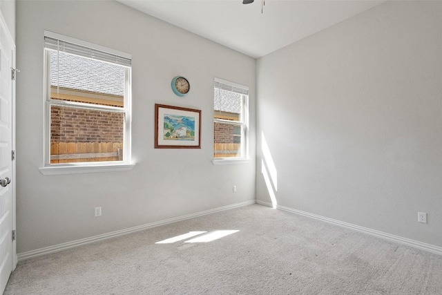 carpeted empty room featuring plenty of natural light, ceiling fan, and baseboards