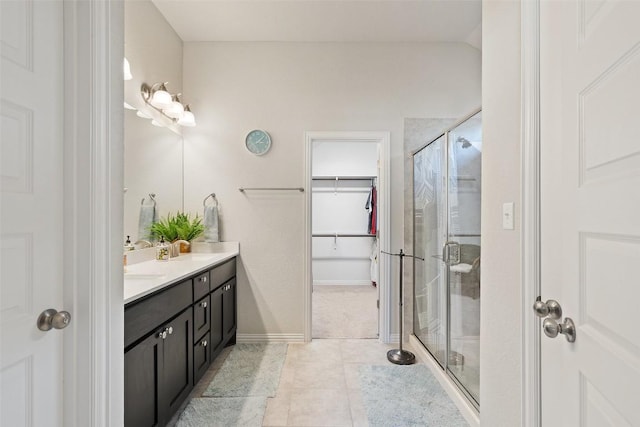 bathroom featuring a spacious closet, vaulted ceiling, a stall shower, tile patterned floors, and vanity