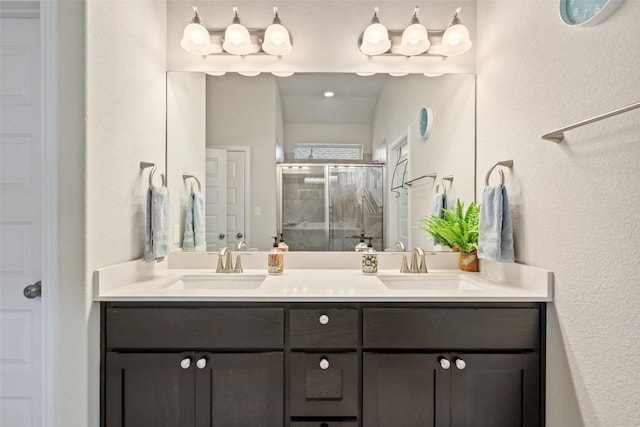 full bath with a sink, a stall shower, and double vanity