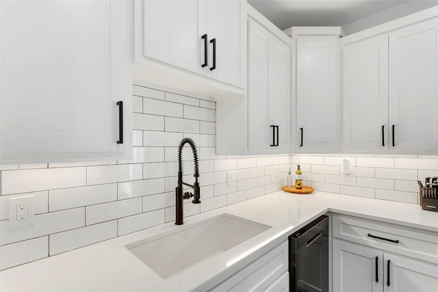 kitchen featuring tasteful backsplash, white cabinets, light countertops, and a sink