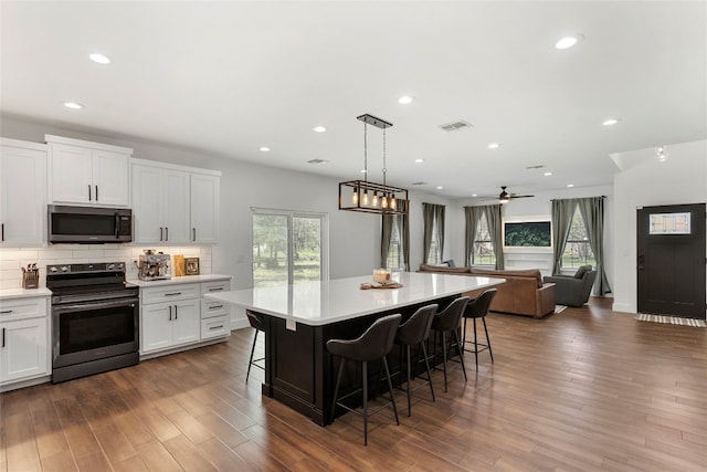 kitchen featuring electric range, dark wood-style floors, visible vents, and backsplash