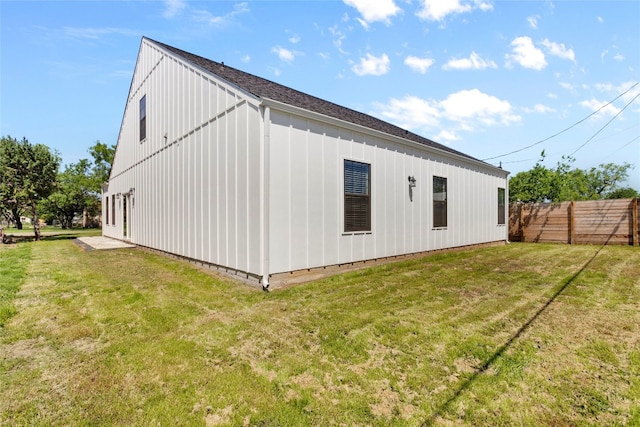 rear view of property with a lawn, board and batten siding, and fence