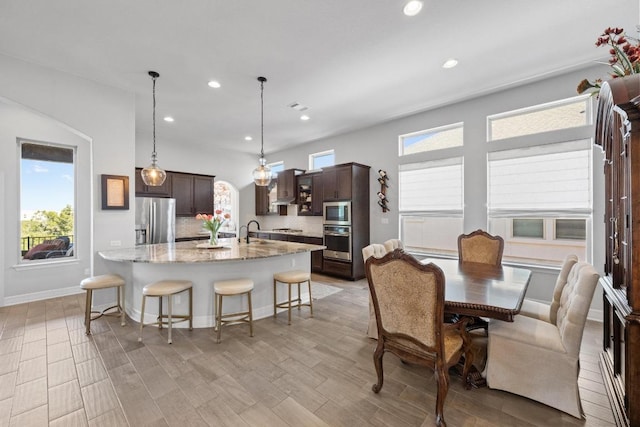 kitchen with dark brown cabinets, appliances with stainless steel finishes, an island with sink, and a kitchen breakfast bar