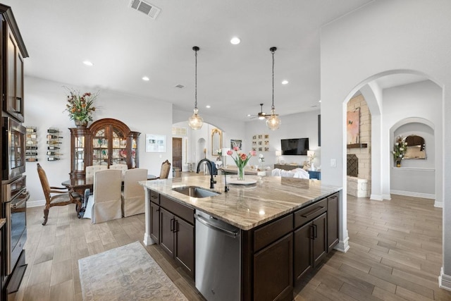 kitchen featuring visible vents, dark brown cabinets, wood finish floors, stainless steel appliances, and a sink