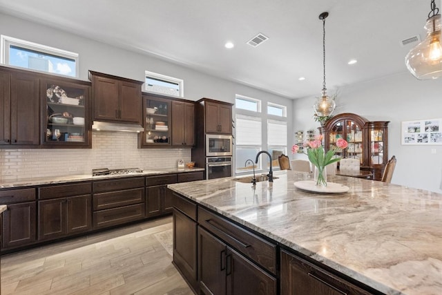 kitchen with under cabinet range hood, visible vents, stainless steel appliances, and a sink