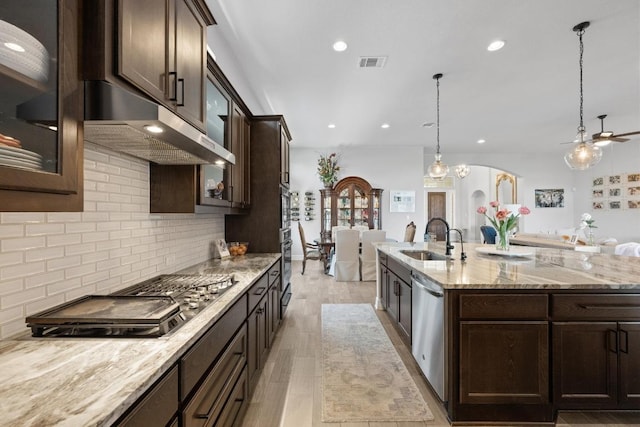 kitchen with visible vents, a sink, stainless steel appliances, dark brown cabinetry, and decorative backsplash