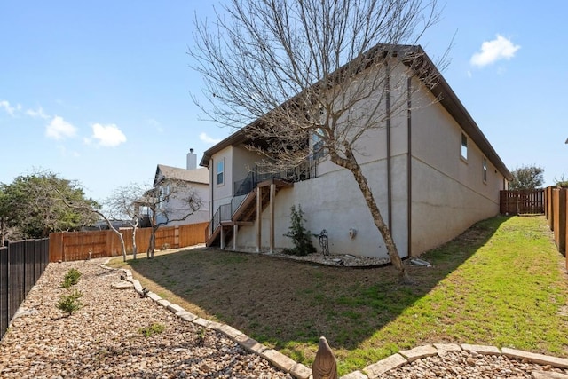 view of home's exterior featuring stairway, a lawn, a fenced backyard, and stucco siding