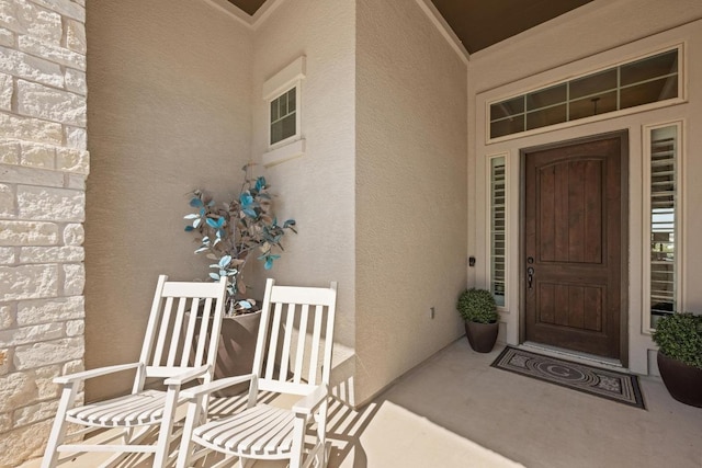 view of exterior entry featuring stone siding and stucco siding