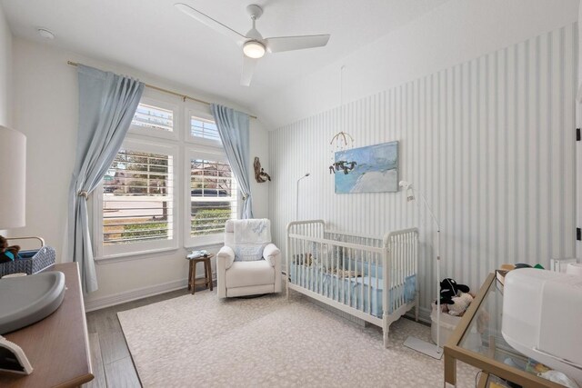 bedroom featuring baseboards, a crib, vaulted ceiling, and wallpapered walls