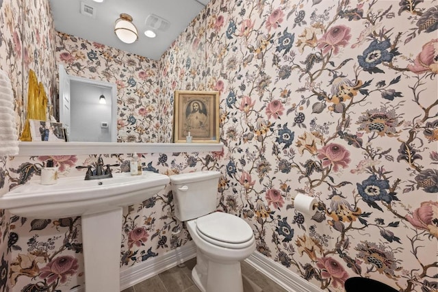 bathroom with wood finish floors, visible vents, toilet, wallpapered walls, and baseboards