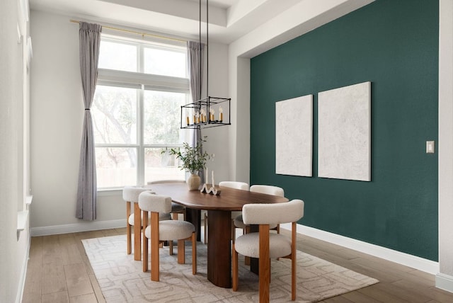 dining room with baseboards, light wood-type flooring, and a chandelier