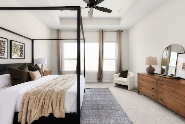 bedroom with ceiling fan, a raised ceiling, baseboards, and light carpet