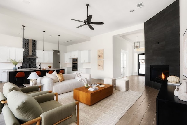 living room featuring a ceiling fan, visible vents, wood tiled floor, recessed lighting, and a large fireplace