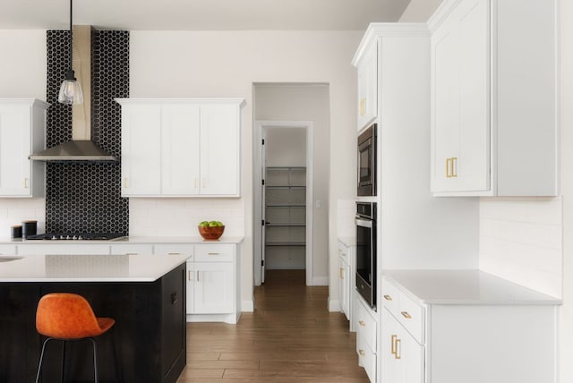 kitchen featuring wood finished floors, built in microwave, oven, light countertops, and wall chimney range hood