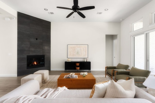 living room featuring visible vents, baseboards, wood finished floors, and a ceiling fan