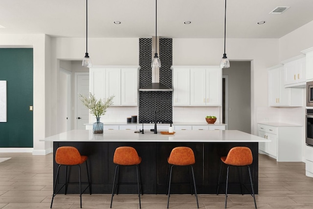 kitchen featuring a spacious island, backsplash, light countertops, light wood-style flooring, and stainless steel appliances