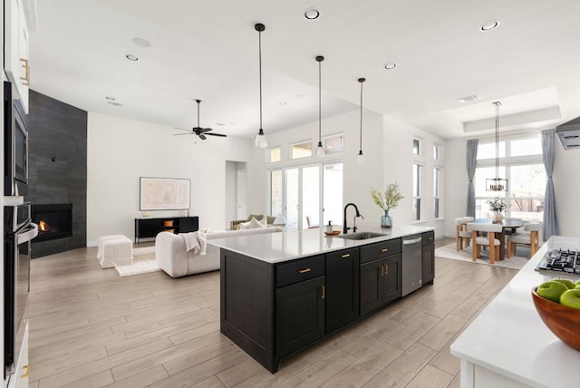 kitchen featuring wood tiled floor, a fireplace, a sink, light countertops, and dark cabinets