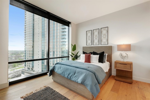 70 Rainey St Unit 1807, Austin, TX 78701 - bedroom featuring expansive windows, multiple windows, and wood finished floors
