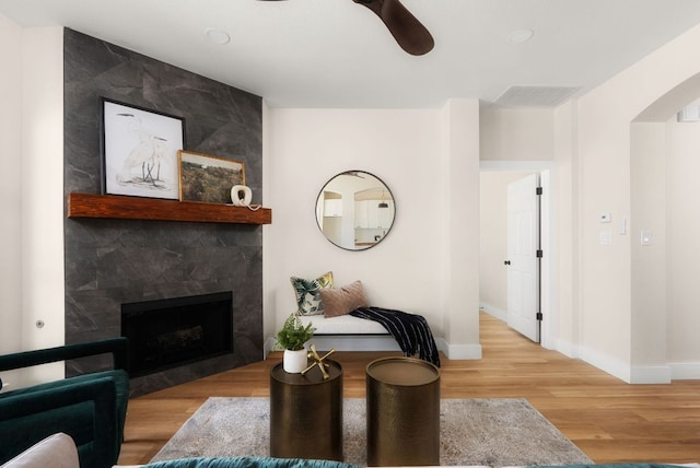 living area with wood finished floors, baseboards, a high end fireplace, and ceiling fan