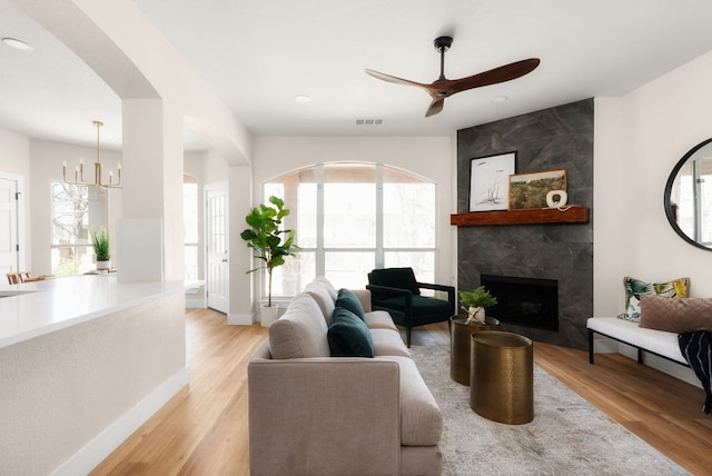 living area featuring light wood-style floors, a ceiling fan, visible vents, and a premium fireplace