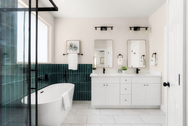 bathroom featuring double vanity, a freestanding tub, a stall shower, and a sink