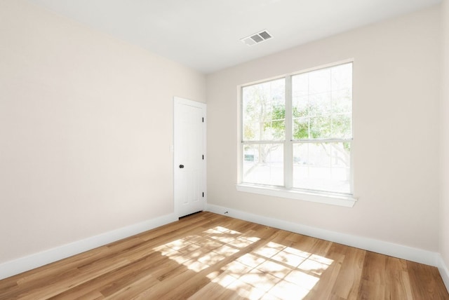 unfurnished room with wood finished floors, visible vents, and baseboards