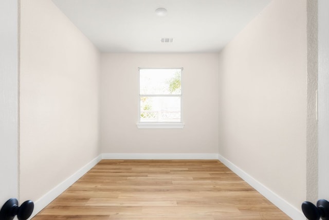 unfurnished room with visible vents, light wood-type flooring, and baseboards