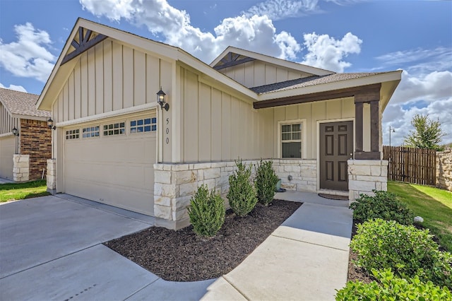 ranch-style home featuring fence, concrete driveway, a garage, stone siding, and board and batten siding