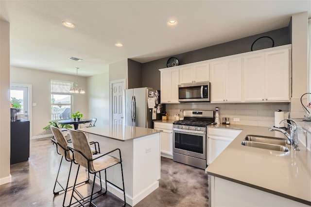 kitchen featuring visible vents, a sink, a kitchen breakfast bar, appliances with stainless steel finishes, and decorative backsplash