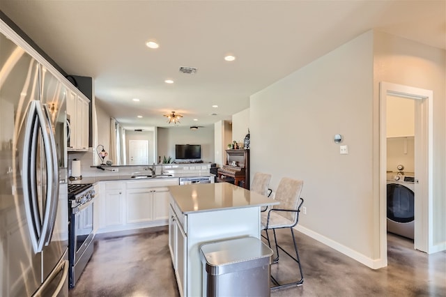 kitchen featuring a kitchen island, white cabinetry, recessed lighting, stainless steel appliances, and washer / dryer