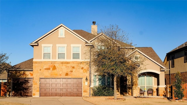 traditional-style house with stucco siding, driveway, stone siding, roof with shingles, and a chimney