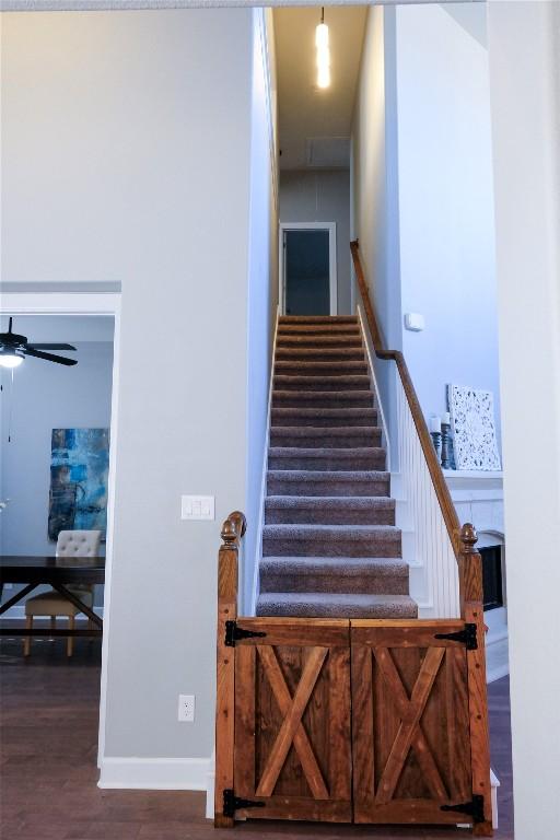 stairs featuring baseboards, wood finished floors, and a ceiling fan