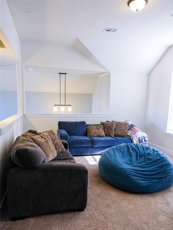 carpeted living room with vaulted ceiling and visible vents