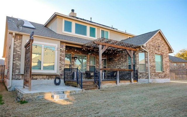 back of property featuring stucco siding, a pergola, a patio, roof with shingles, and brick siding