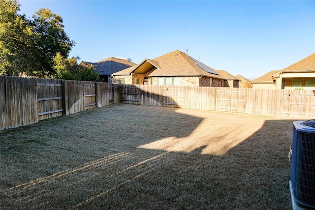 view of yard with central AC unit and a fenced backyard