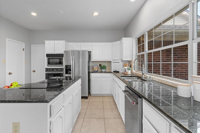 kitchen featuring black appliances, dark stone countertops, light tile patterned flooring, white cabinetry, and a sink