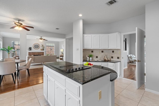 kitchen featuring visible vents, a center island, ceiling fan, light tile patterned flooring, and black electric cooktop