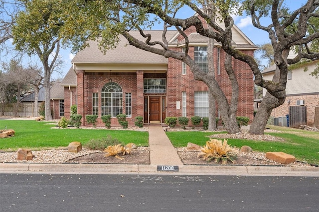 traditional-style house with brick siding and a front lawn