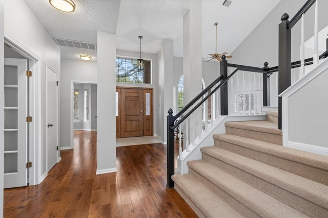 foyer with visible vents, a high ceiling, ceiling fan, stairs, and hardwood / wood-style flooring