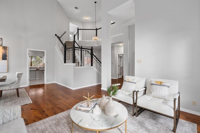 living room featuring visible vents, baseboards, a high ceiling, stairs, and wood-type flooring